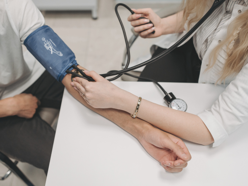 A healthcare professional measures the blood pressure of a patient.